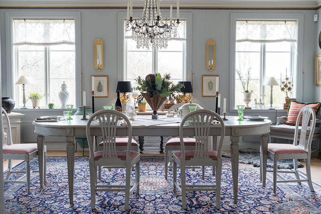 White table, chandelier and blue Oriental rug in dining room