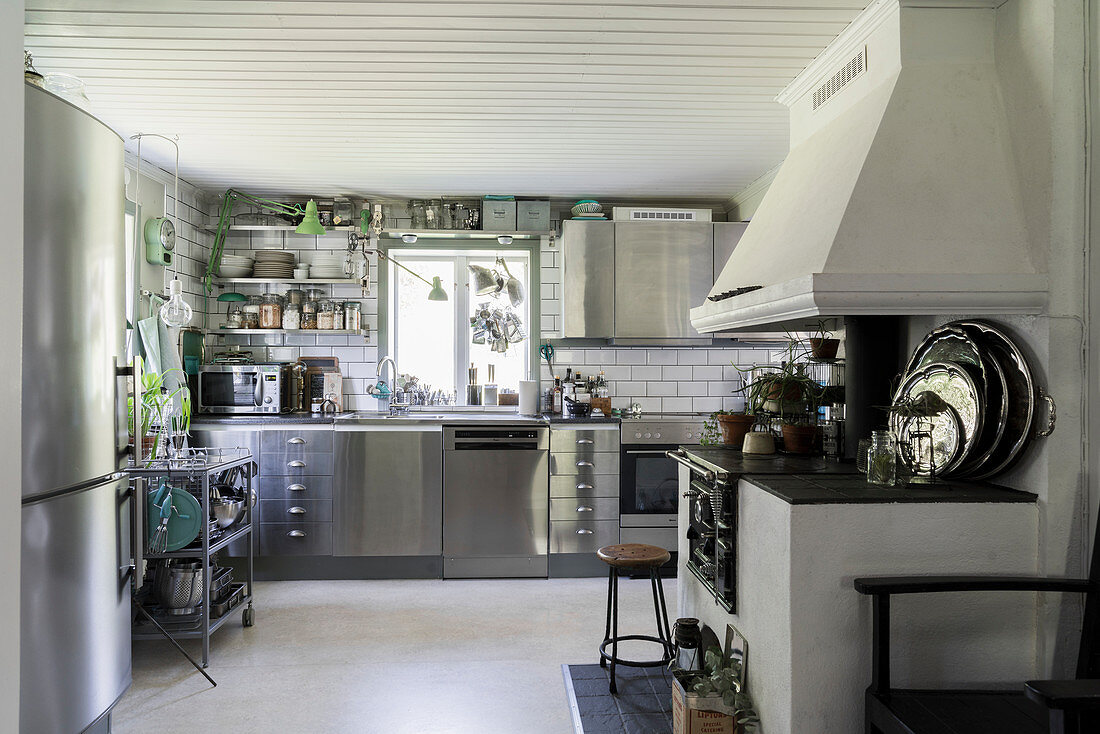 Weiße Küche mit dekorativem alten Holzofenherd und modernen Edelstahlfronten