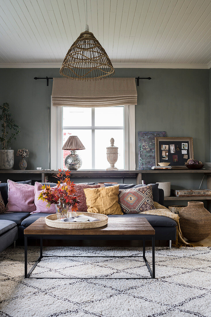 Corner sofa and ethnic accessories in interior with grey walls