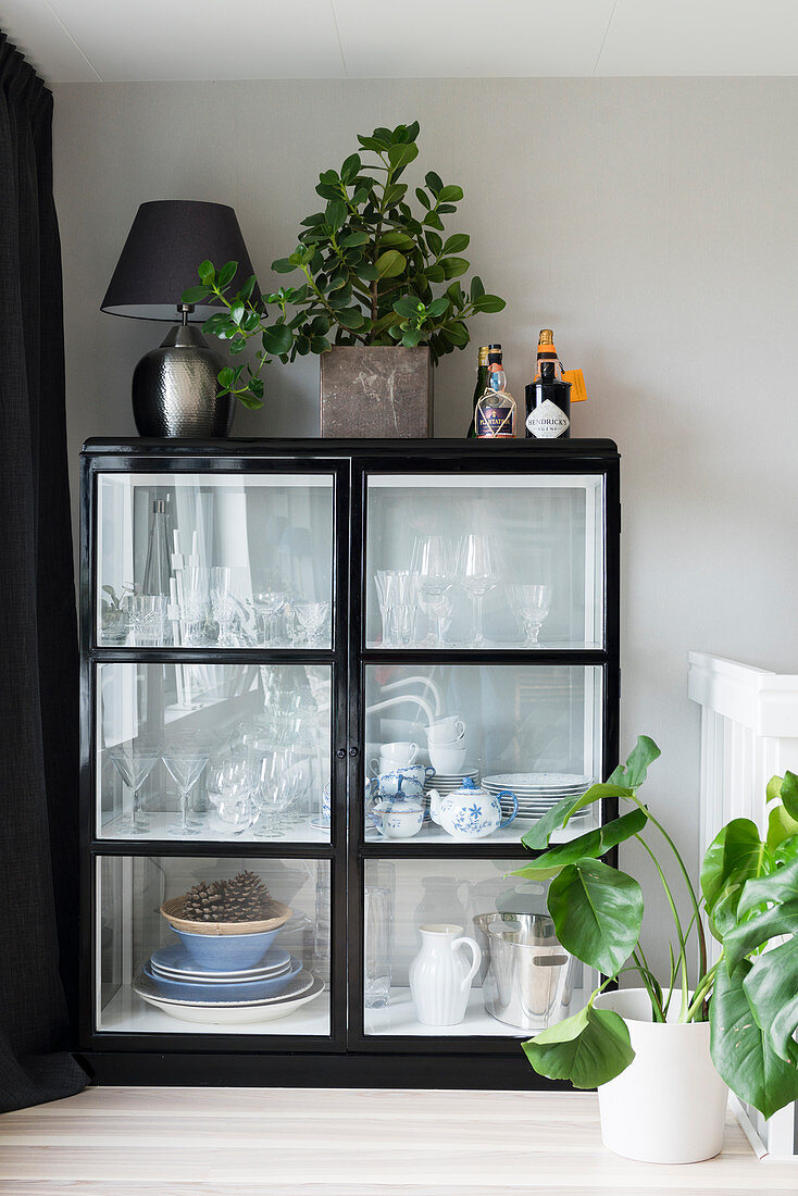 Crockery and glasses in black, half-height, glass-fronted cabinet