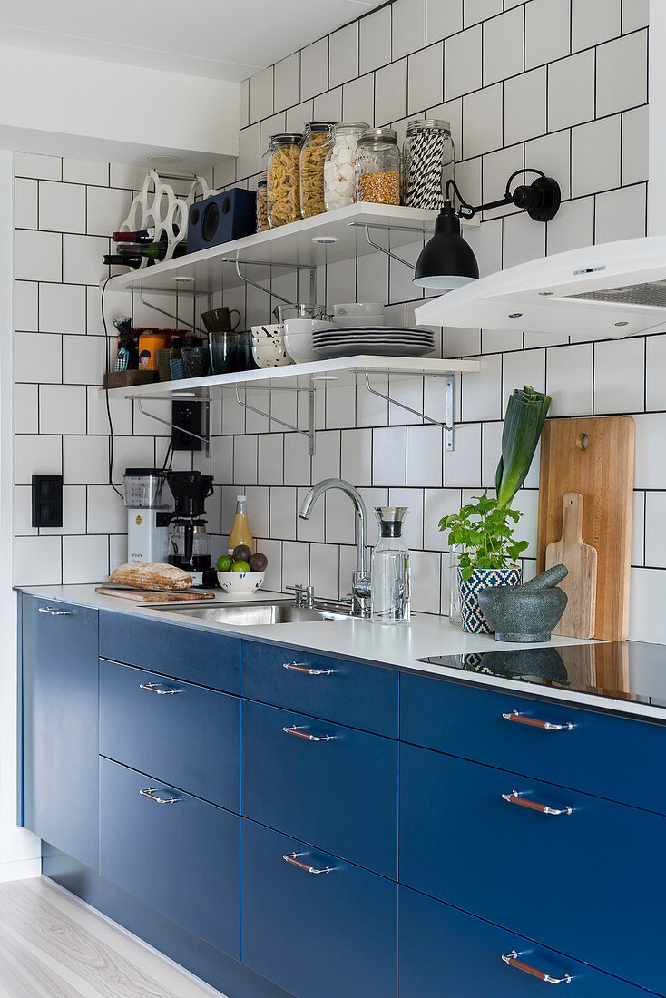 Küche mit blauen Fronten und weißen Fliesenwänden