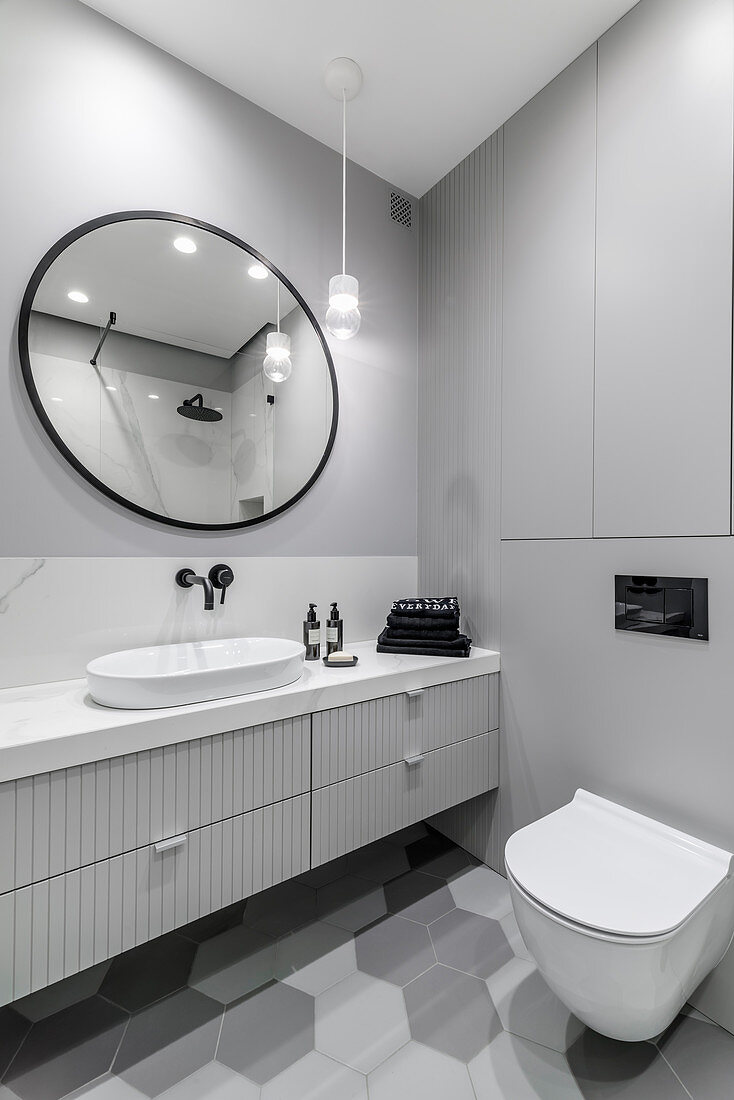 Waschtischmöbel mit Schubladen, Wandspiegel und Toilette im Badezimmer