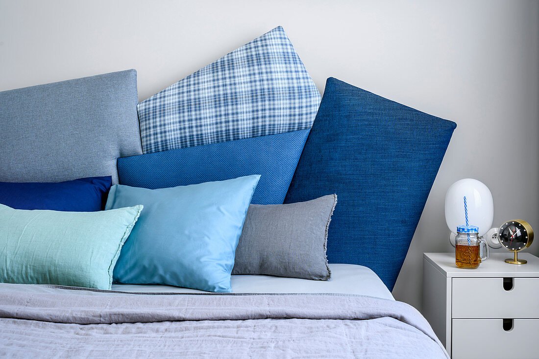 Cushions in shades of blue on double bed and bedside table in bedroom