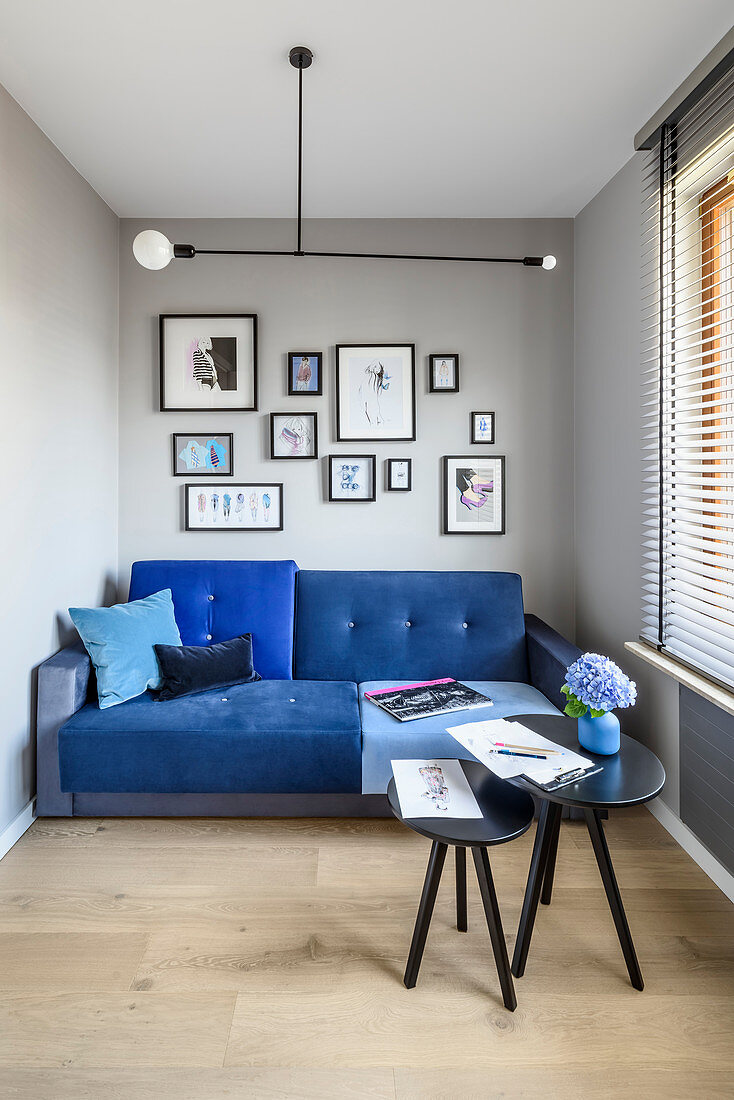 Blaues Sofa und Beistelltische in schmalem Wohnzimmer mit grauen Wänden