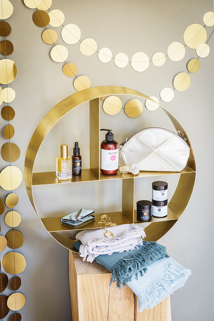 Golden garland above round shelving unit containing bathroom supplies