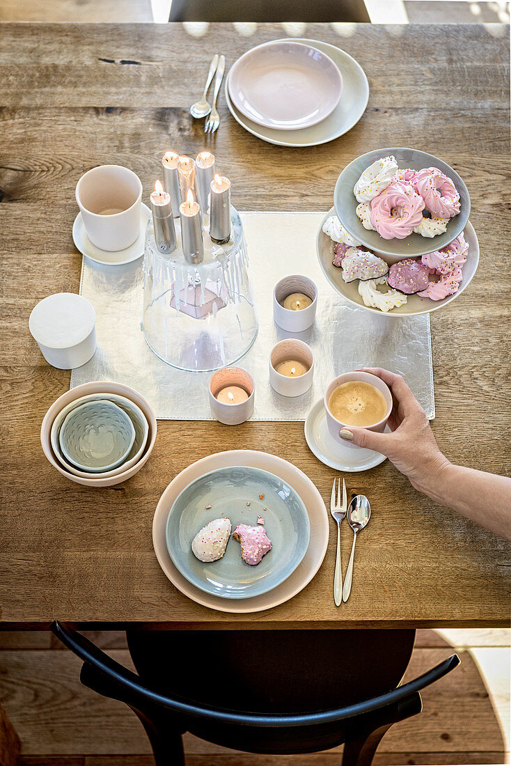 Hand stellt Tasse Kaffee auf romantisch gedeckten Tisch
