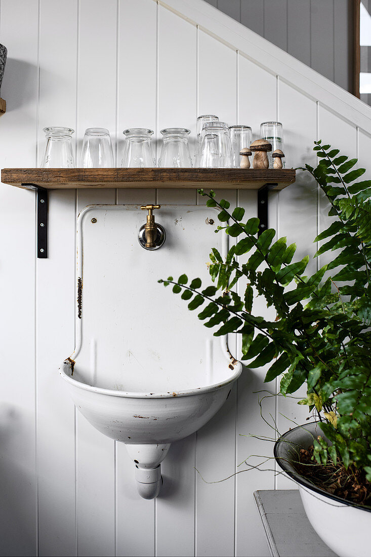 Shelf with drinking glasses over the old enamel sink