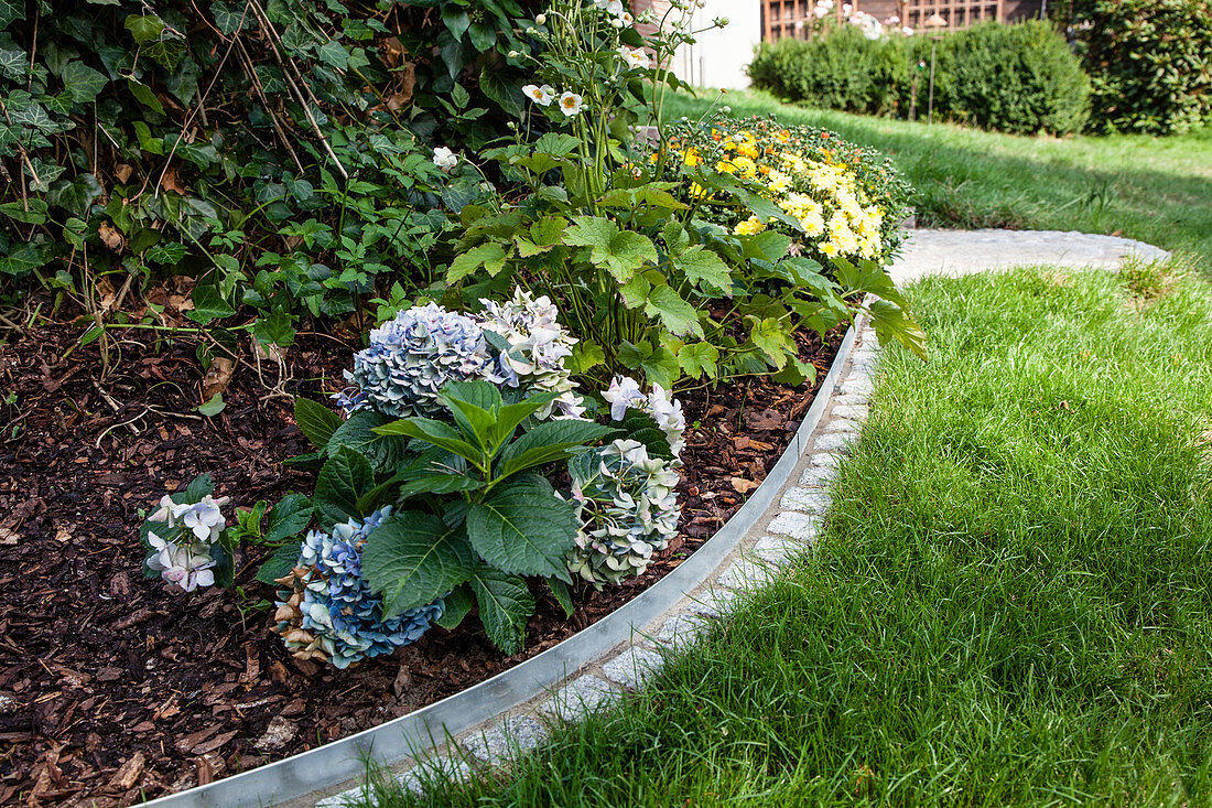 DIY metal and stone edging around flowerbed
