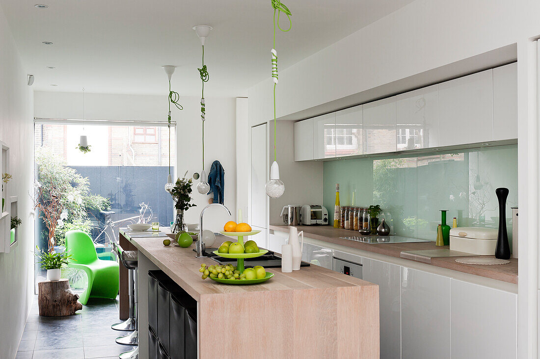 White, high-gloss cupboards and pale wooden island counter in modern kitchen