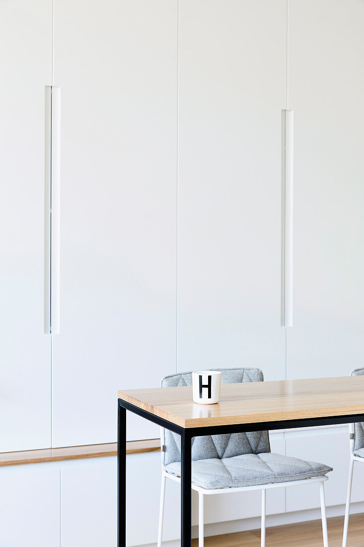 Wooden table with black metal frame in front of plain white wall unit