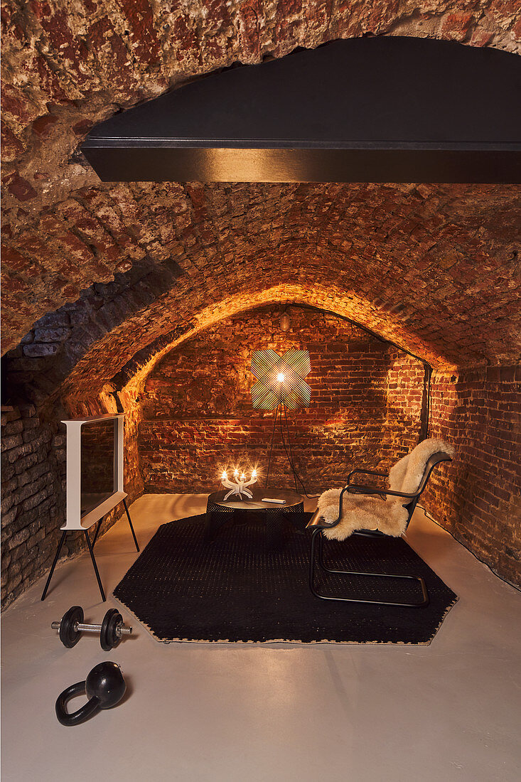 Exercise equipment and cosy seating area in renovated vaulted cellar