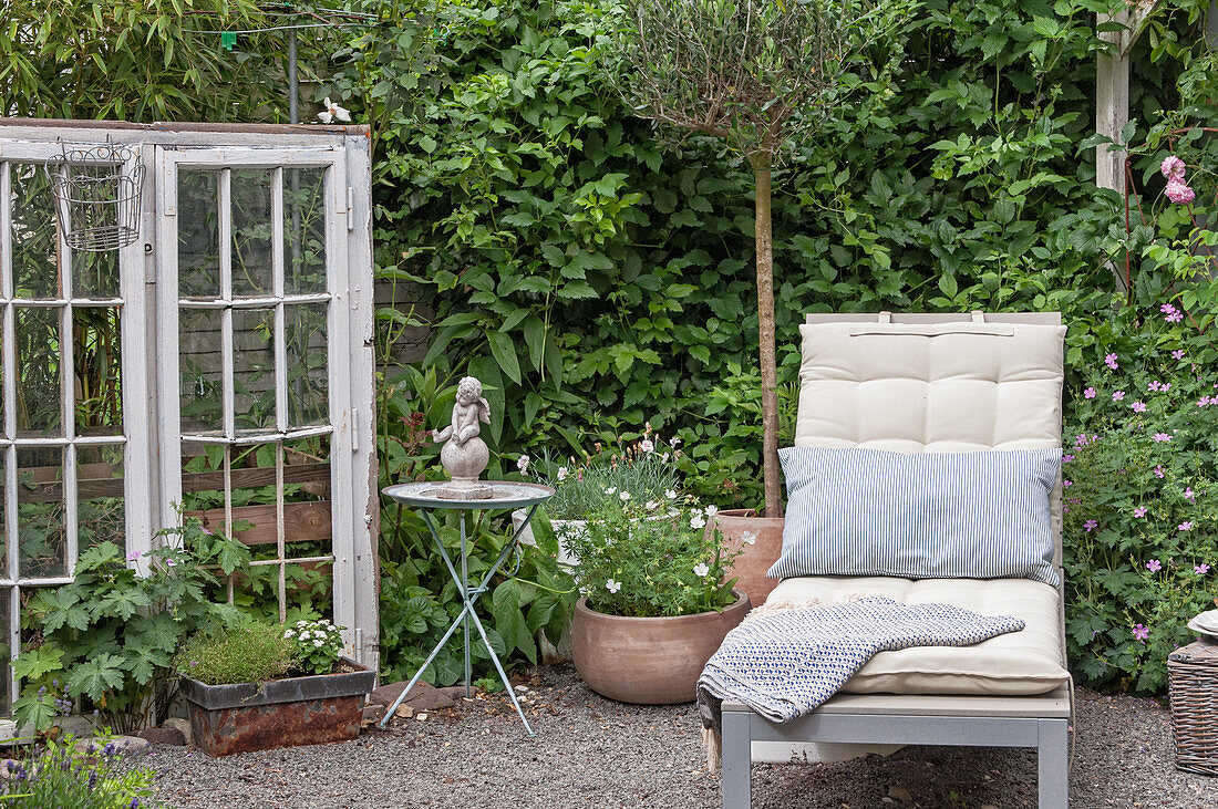 A quiet corner in the garden with a sun lounger, antique window, and decorations