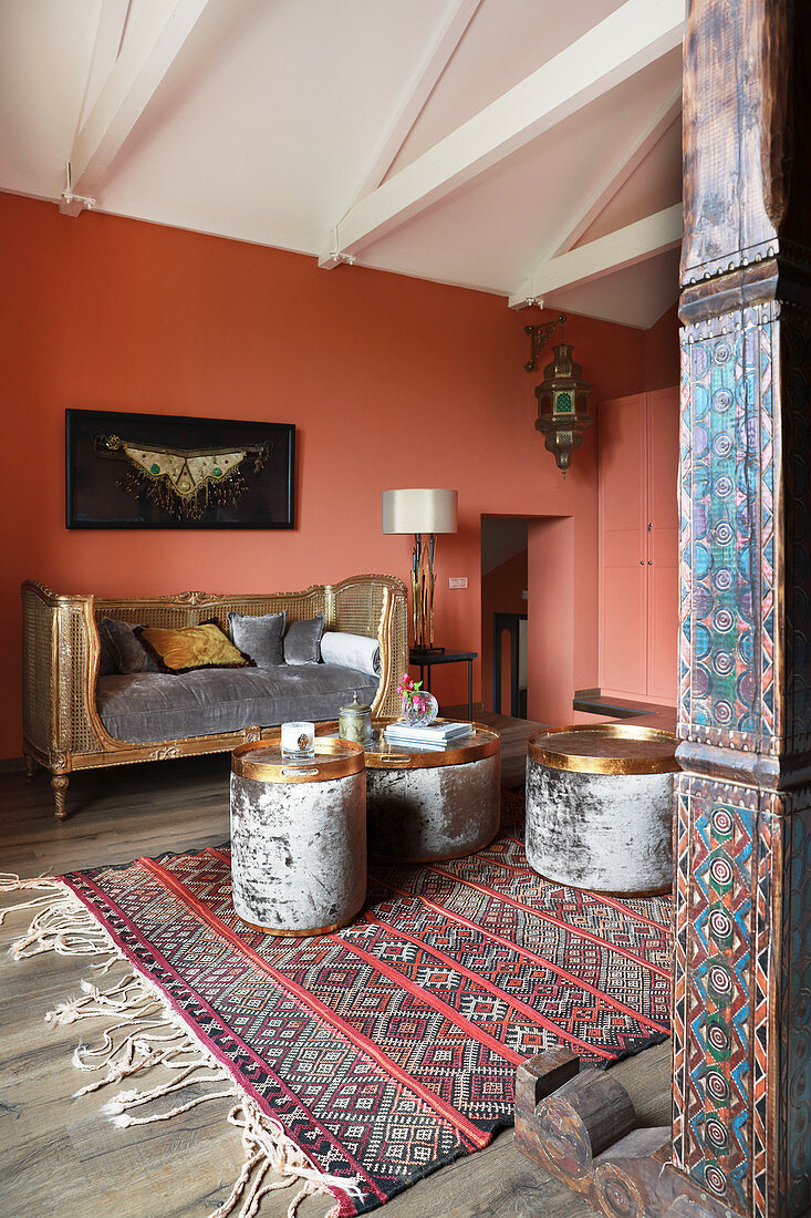 Goldfarbenes, antikes Tagesbett und Beistelltische im Zimmer mit lachsfarbenen Wänden