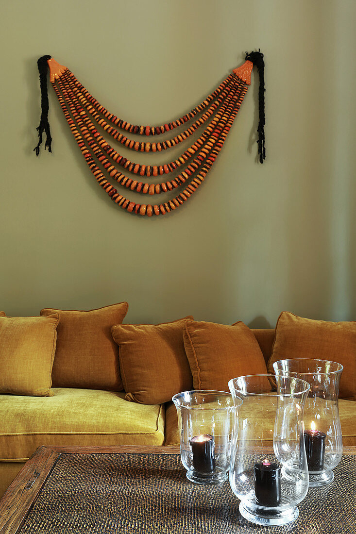 Sofa and wall hanging behind candle lanterns on coffee table