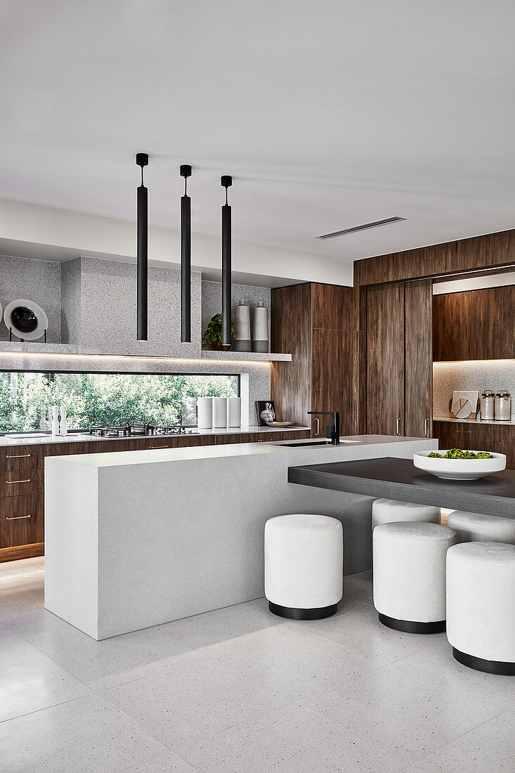 Open-plan designer kitchen with partition counter and white stools in dining area