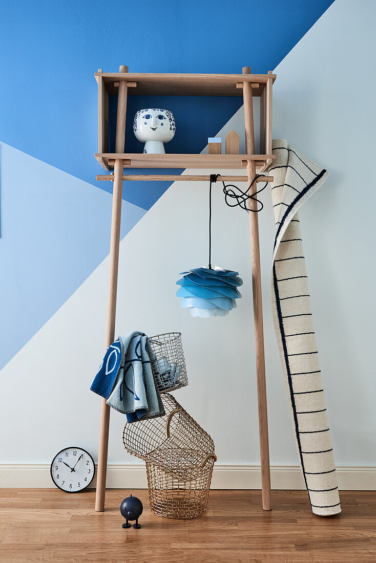 Helles Holzregal mit Dekoobjekten vor blauer Wand