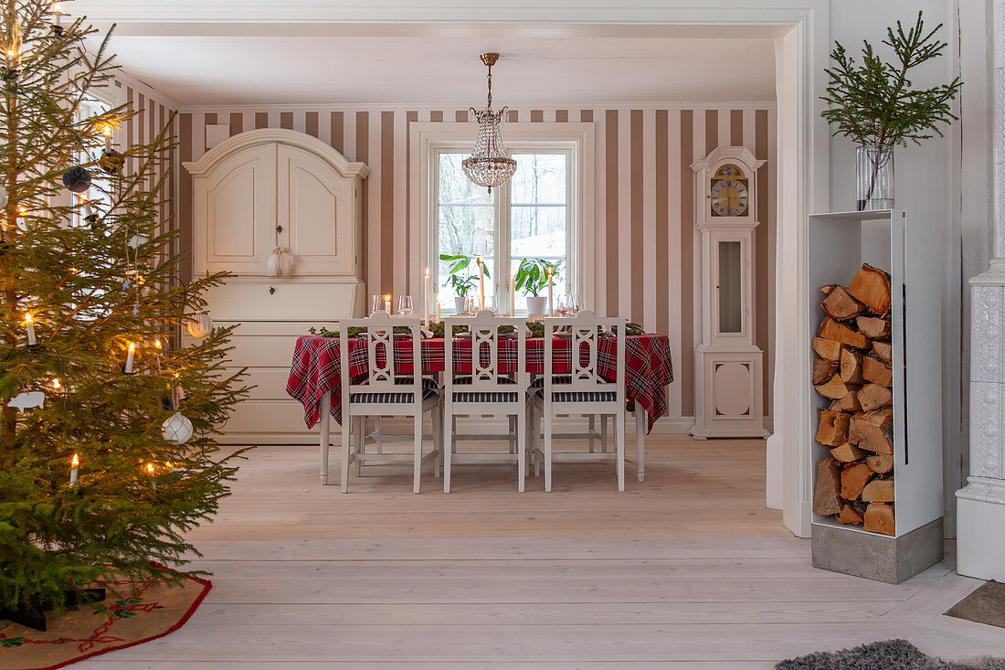Decorated Christmas tree, stacked firewood and Scandinavian dining area