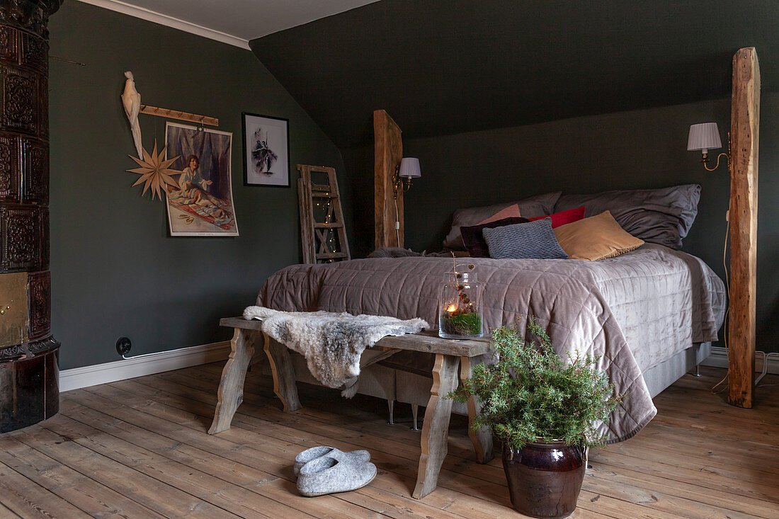 Box spring bed between rustic wooden columns below sloping ceiling