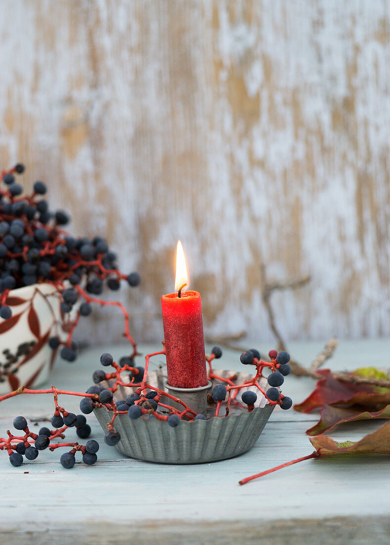 Kerze mit Kerzenhalter aus Blech und Beeren vom wilden Wein