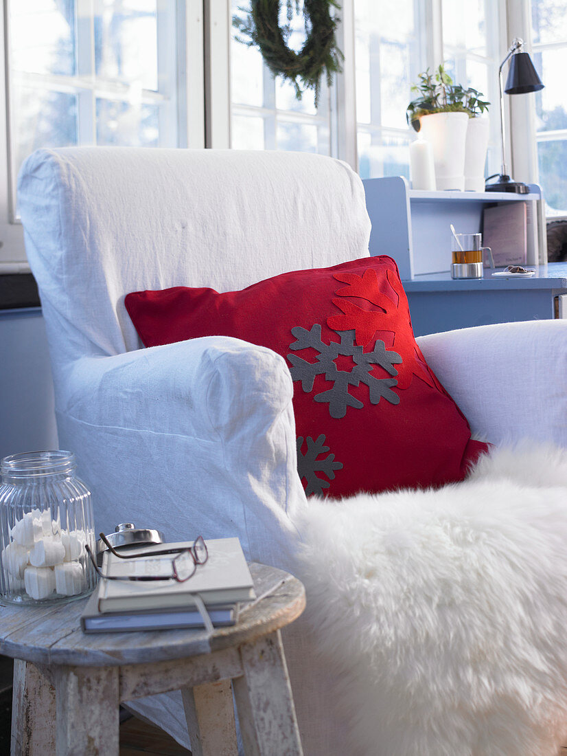 Rotes Kissen mit Schneeflocken aus Filz auf einem Sessel mit Fell