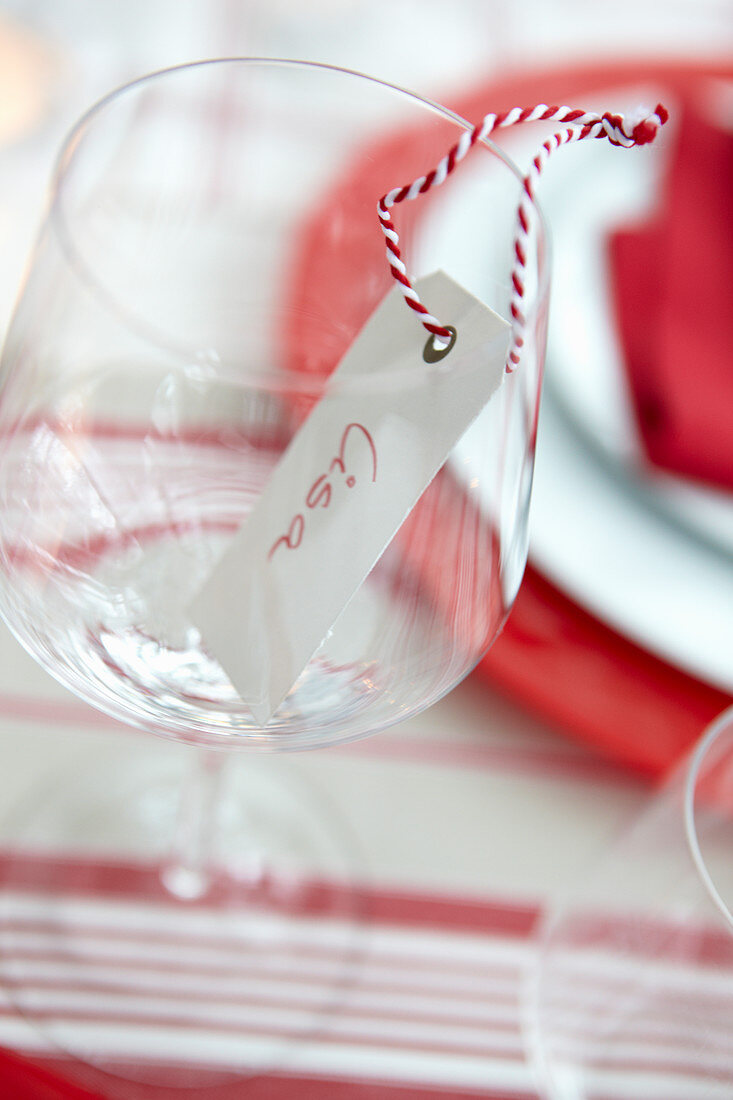 Namensschild mit rot-weißem Bäckergarn im Weinglas