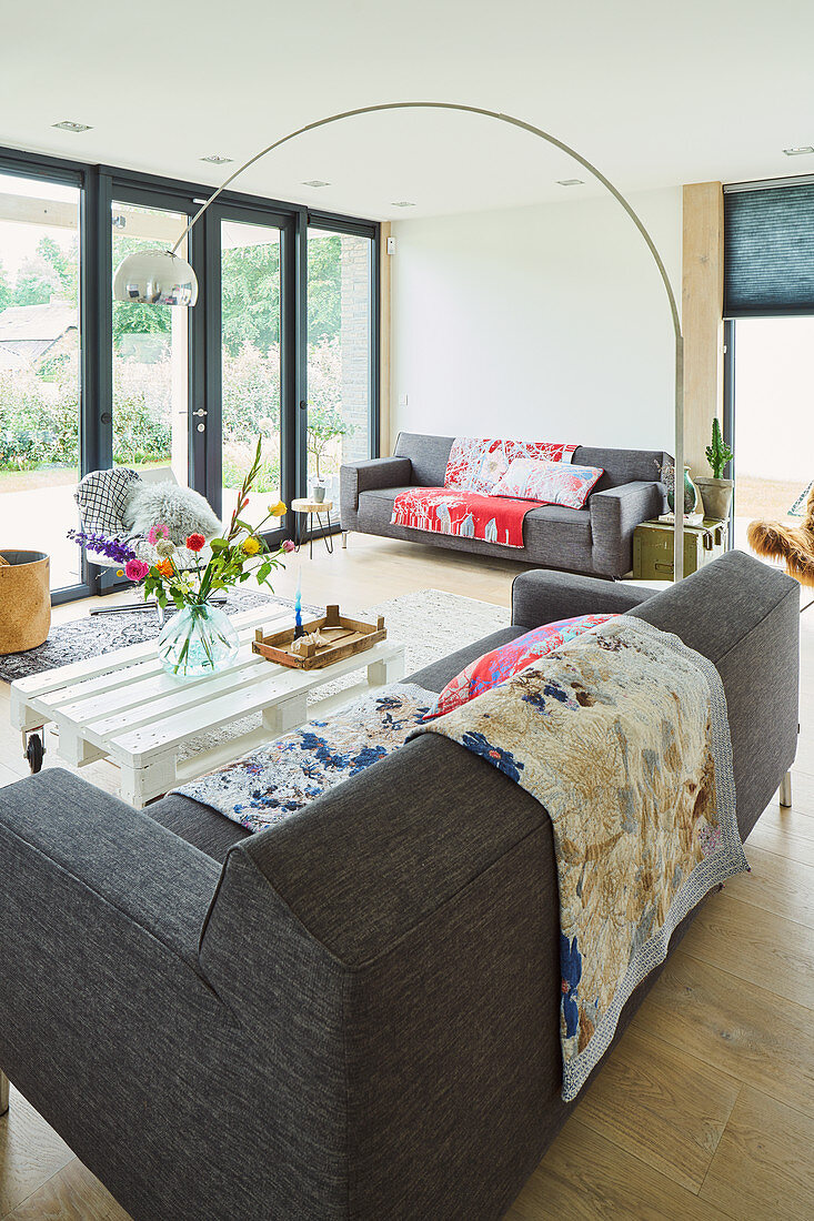 Sitzbereich im Wohnzimmer mit grauen Sofas und weißem Palettentisch