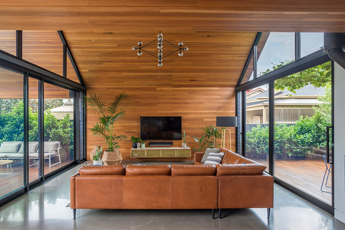 Übereck-Sofa in Wohnraum unter Spitzdach mit beidseitigen deckenhohen Fensterfronten