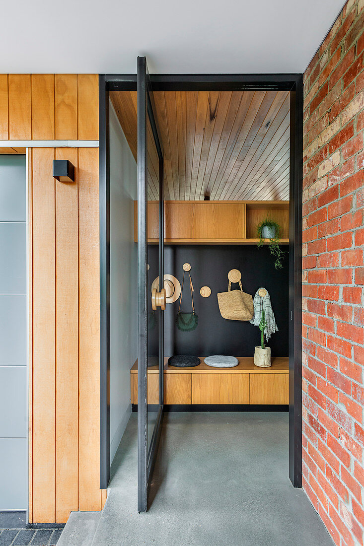 Entrance area with glass swing door and wooden wardrobe with black back wall