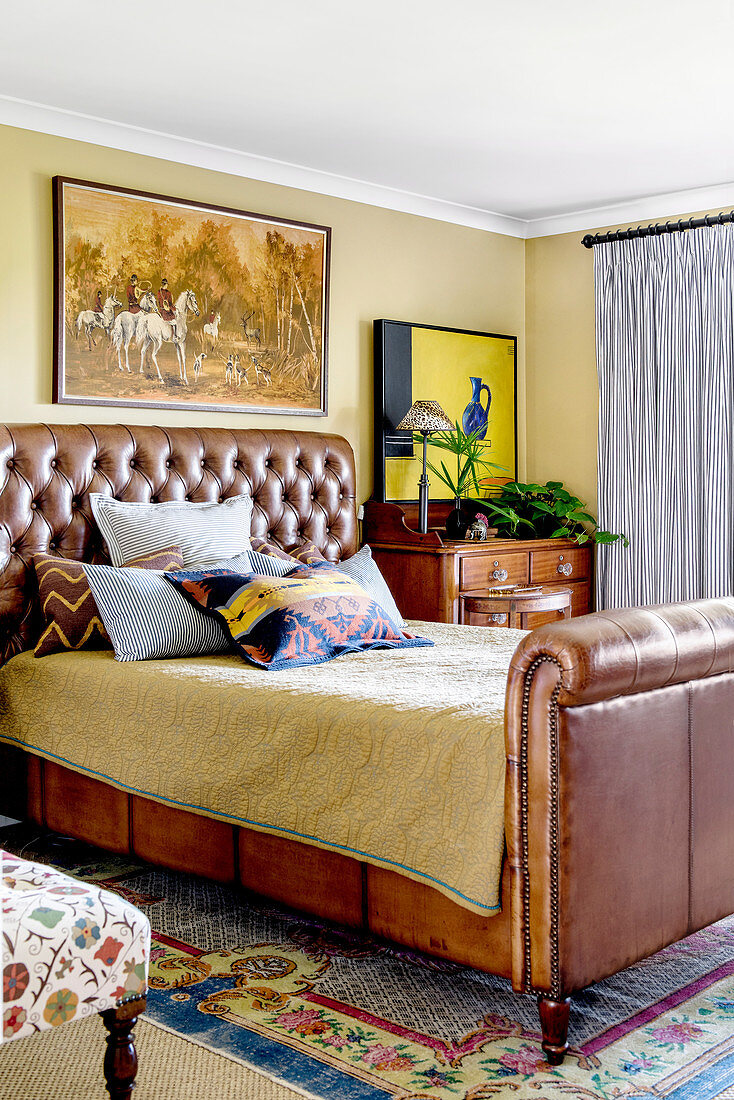 Bedroom with hunting painting over brown leather bed
