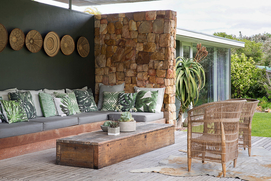 Leaf-patterned scatter cushions on corner sofa on exotic terrace