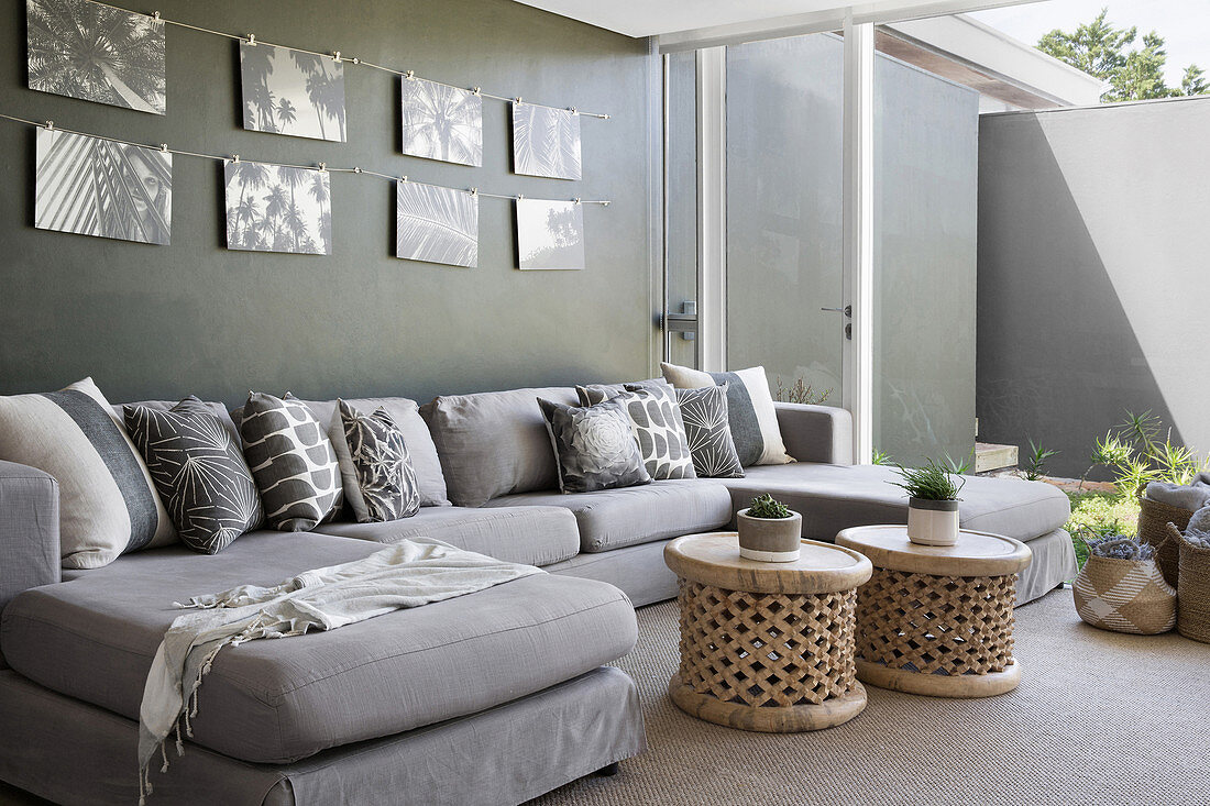 Bilder mit Palmenmotiven überm Sofa im exotischen Wohnzimmer