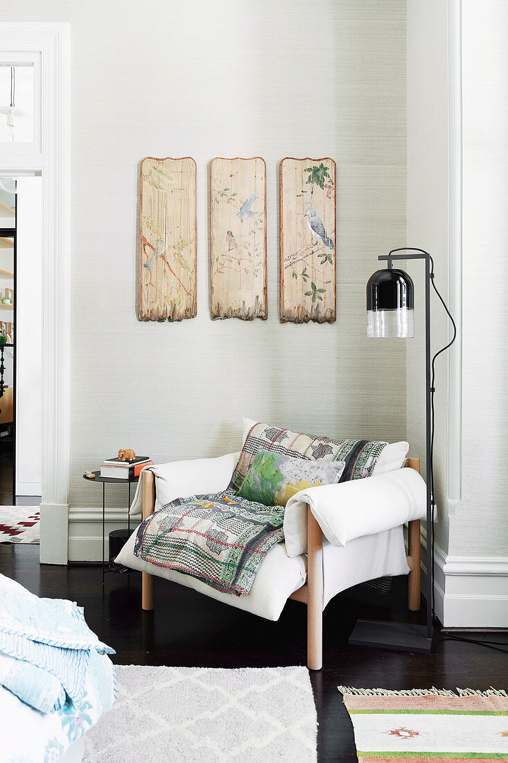 Sitting area with antique hand-painted wall panels over white upholstered armchair