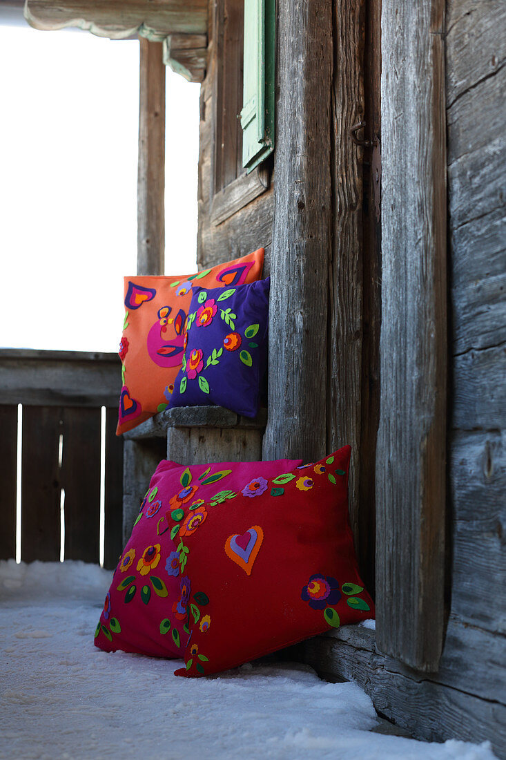 Farbenfrohe Zierkissen folkloristisch dekoriert mit verschiedenen Filzmotiven