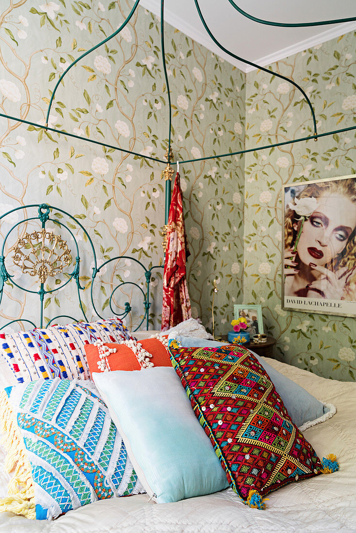 Schlafzimmer im Boho-Stil mit farbenfrohen Dekokissen auf verschnörkeltem Himmelbett