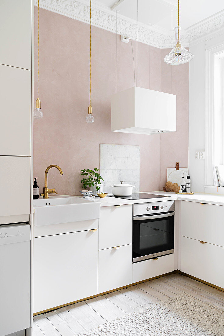 White fitted kitchen with stucco ceiling and powder-pink wall