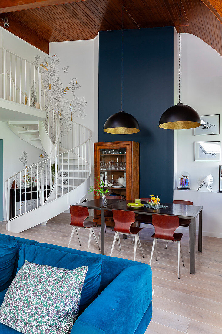 Blaues Samtsofa und Essbereich mit Tisch und antikem Geschirrschrank in Maisonette-Wohnung
