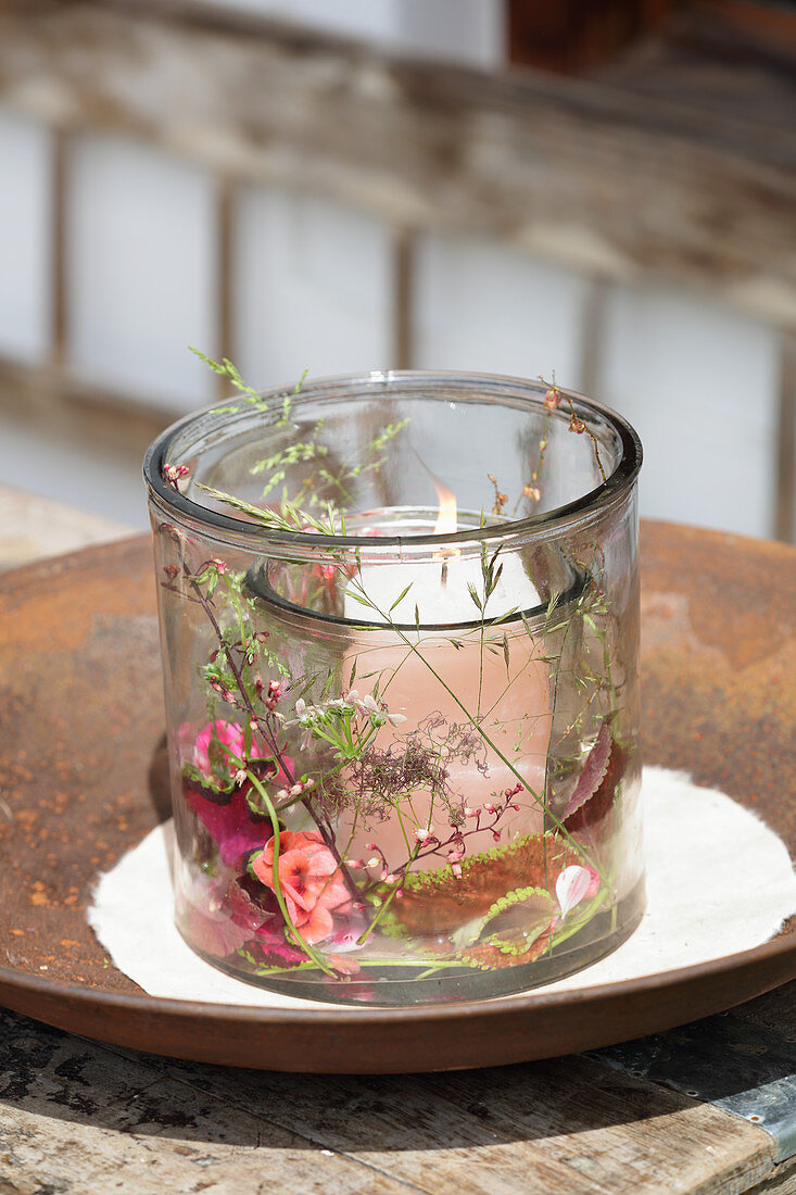 Glass candle lantern decorated with summer flowers, leaves and grasses