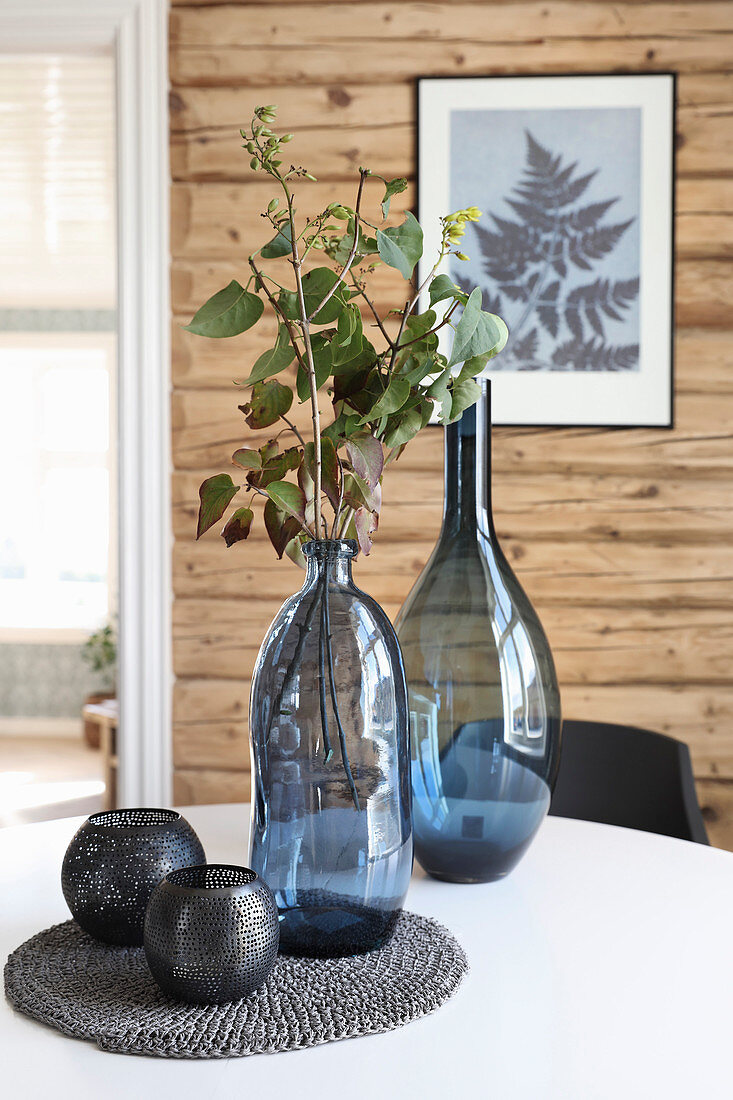 Blue glass vases and black tealight holders on table