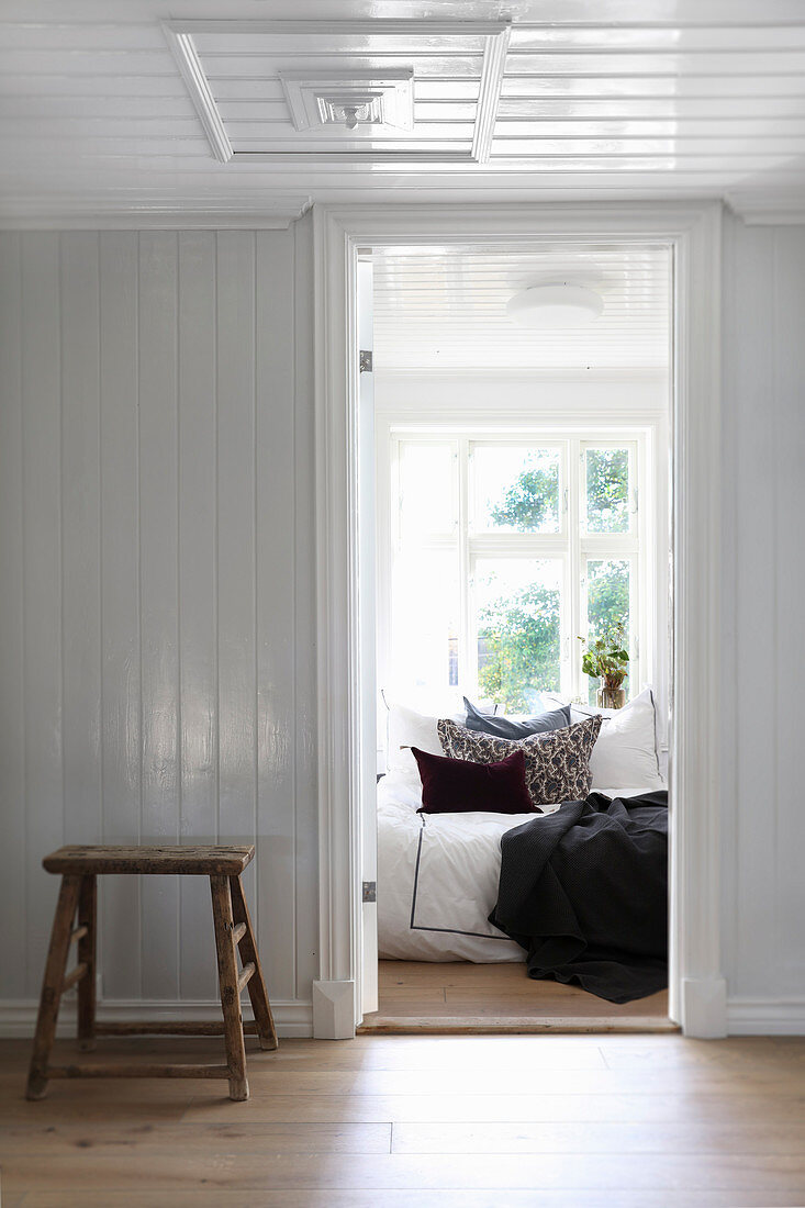 View from hallway with wood-clad walls into bright bedroom