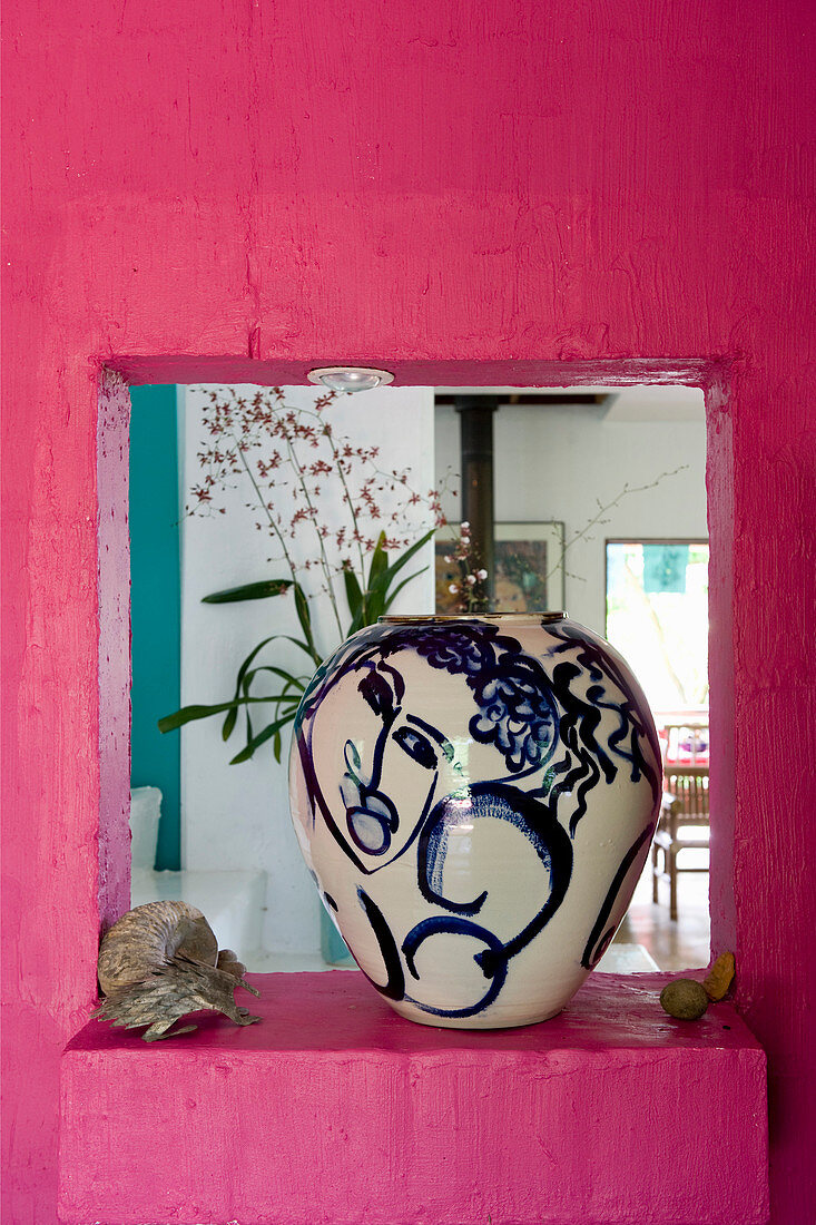 Blau bemalte Vase in einem Durchbruch in pinker Wand