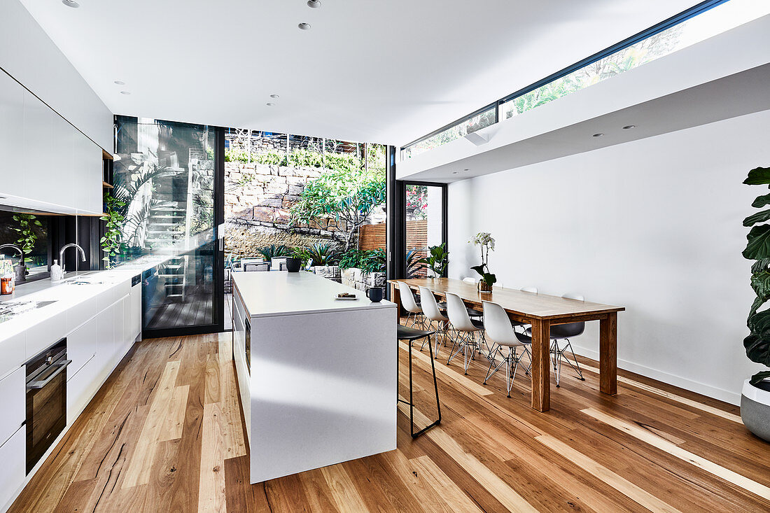 Große moderne Wohnküche mit langem Esstisch und Gartenzugang