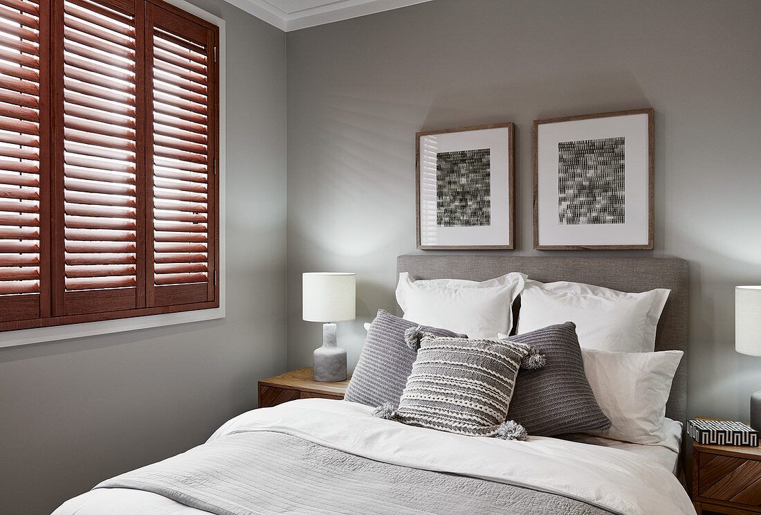 Bedroom in shades of grey and white with closed window shutters