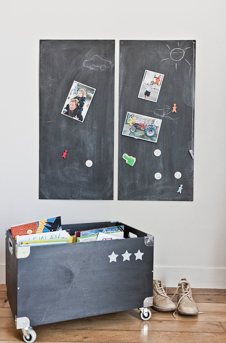 Two chalkboards on wall above wooden toy box