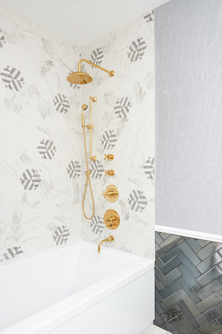 Bathroom shower with hexagon marble tiles, brass fittings and blue glossy subway tiles in zigzag pattern on wall