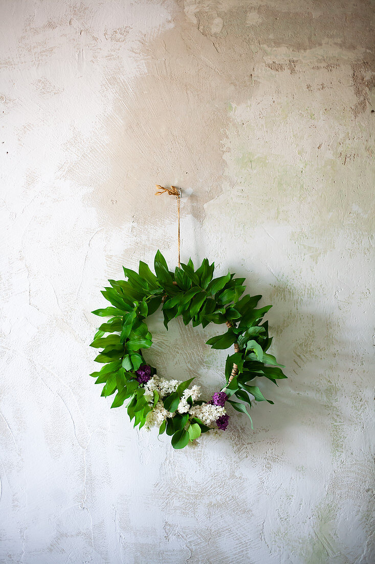 Wreath of lilac and lily-of-the-valley leaves on wall