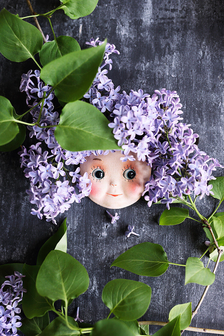 Puppengesicht mit lila Fliedern