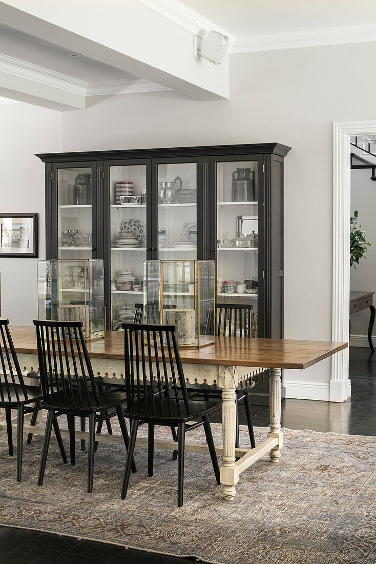 Glass-fronted cabinets and antique dining table with wooden chairs in dining area