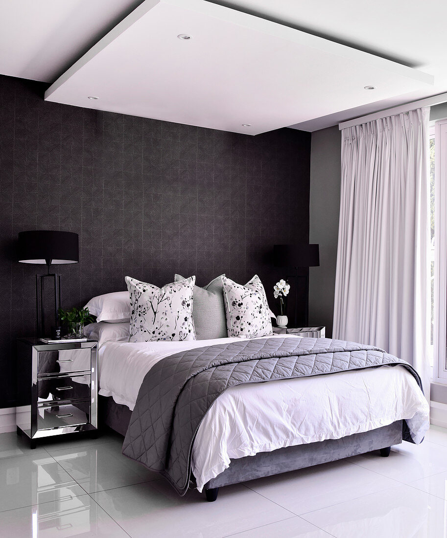 Double bed in bedroom with shiny tiled floor, black wallpaper and ceiling panel