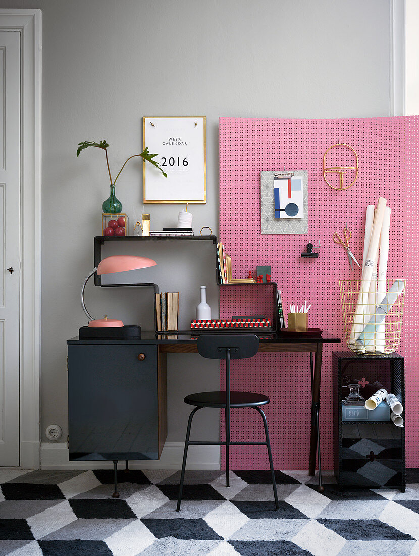 Home Office mit schwarzen Möbeln, grauer Wand und rosa Pinnwand