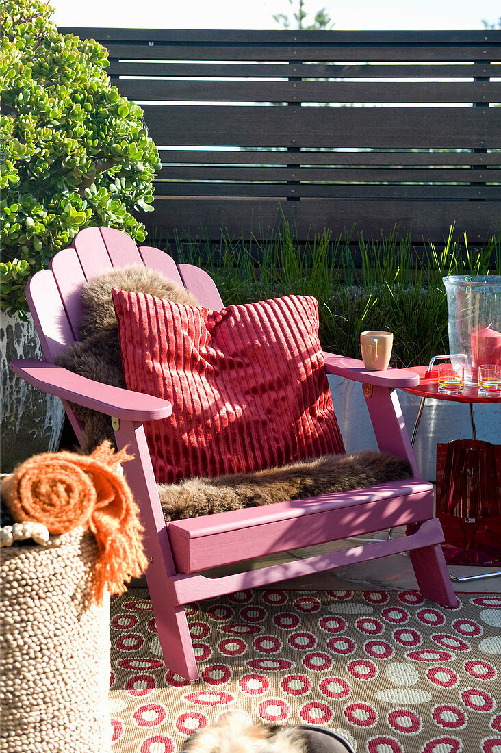 Pinker Deckchair mit Fell und Kissen auf der gemütlichen Terrasse